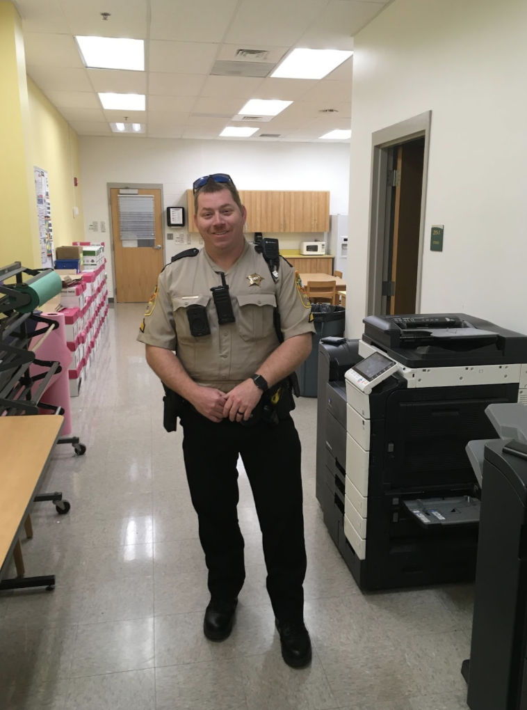 Harris poses in the teacher work room next to the printer where he prints off a paper.